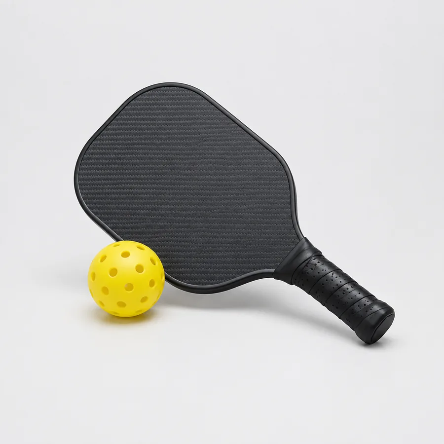 Pickleballracket i kolfiber bredvid en gul pickleballboll